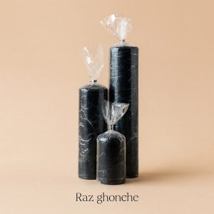 three glossy black pillar candles in different heights wrapped in clear plastic, minimal beige background, RAZ GHONCHE