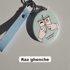 cute round keychain with illustration of two hands holding coffee cups, one with a mustache and one with a lipstick mark, text “Love without end hath no end”, light blue strap, RAZ GHONCHE
