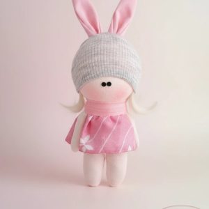 handmade russian cloth doll with pale pink plush body, gray knitted hat topped with white pom‑pom, blue and white checkered dress, and fluffy white mini‑balls around collar, RAZ GHONCHE