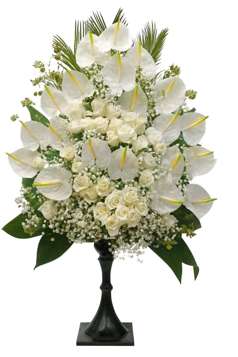 Luxury white sympathy flower arrangement with white anthuriums, white roses and gypsophila on a black stand.