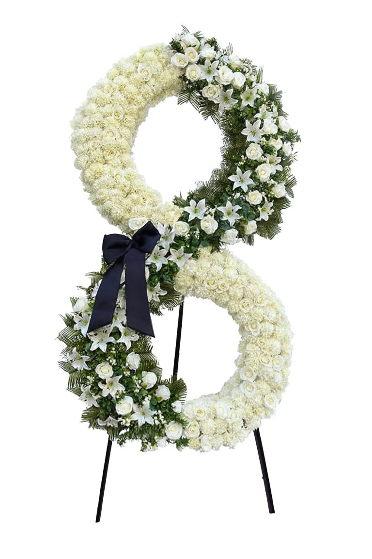 Luxury double-ring white floral stand with lilies, roses, greenery and black ribbon on a tripod.