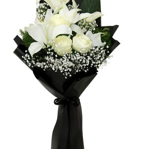 Elegant funeral bouquet with white lilies, white roses, and baby's breath wrapped in glossy black paper and tied with a black ribbon on a white background.
