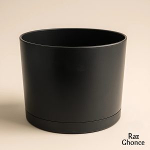 Black cylindrical plastic pot with an integrated saucer, featuring a simple and modern design, placed on a light-colored surface with a clear “Raz Ghonche” watermark.
