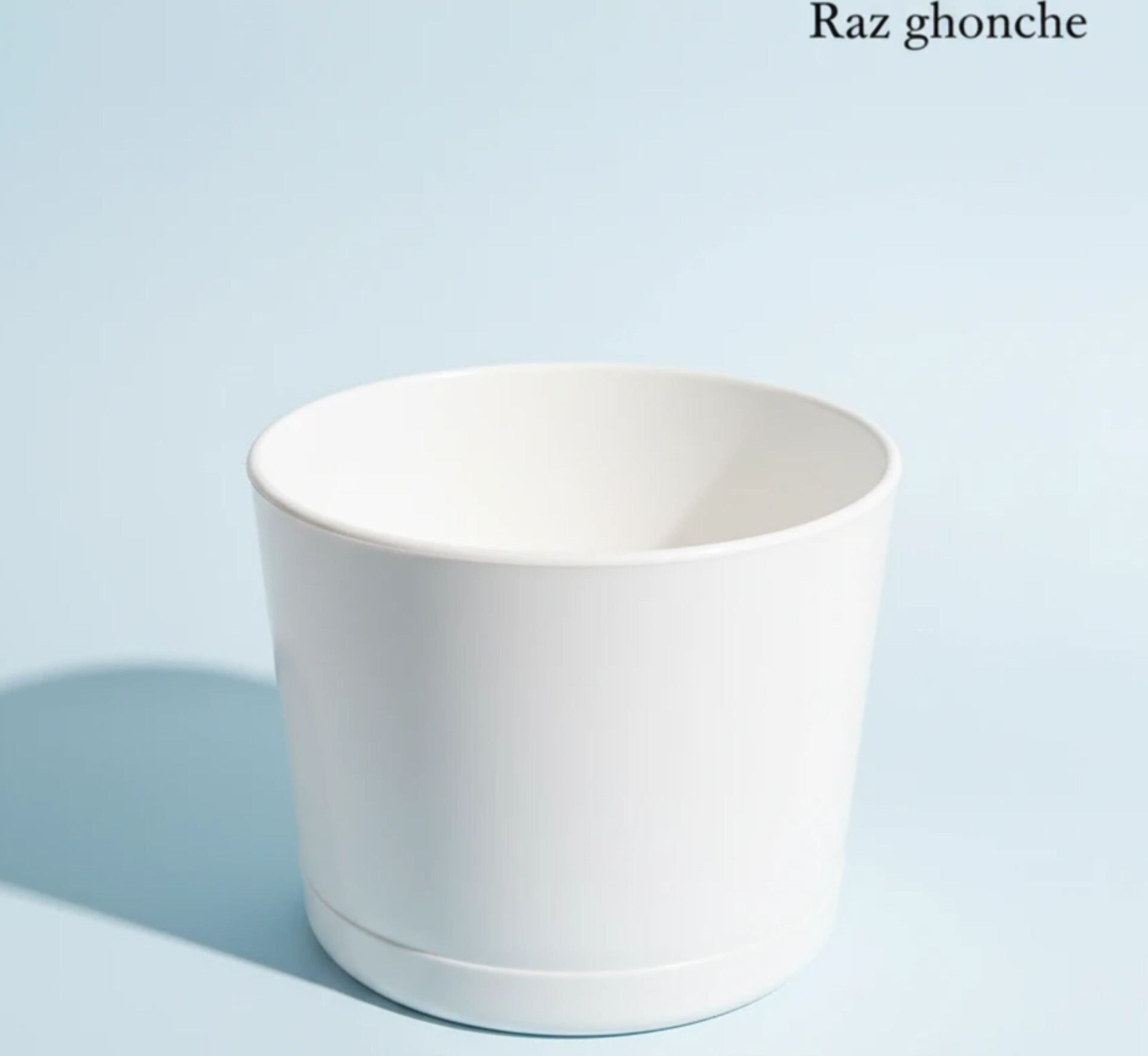 White cylindrical plastic pot with an integrated saucer, designed for plants, placed on a light blue background with a visible shadow.